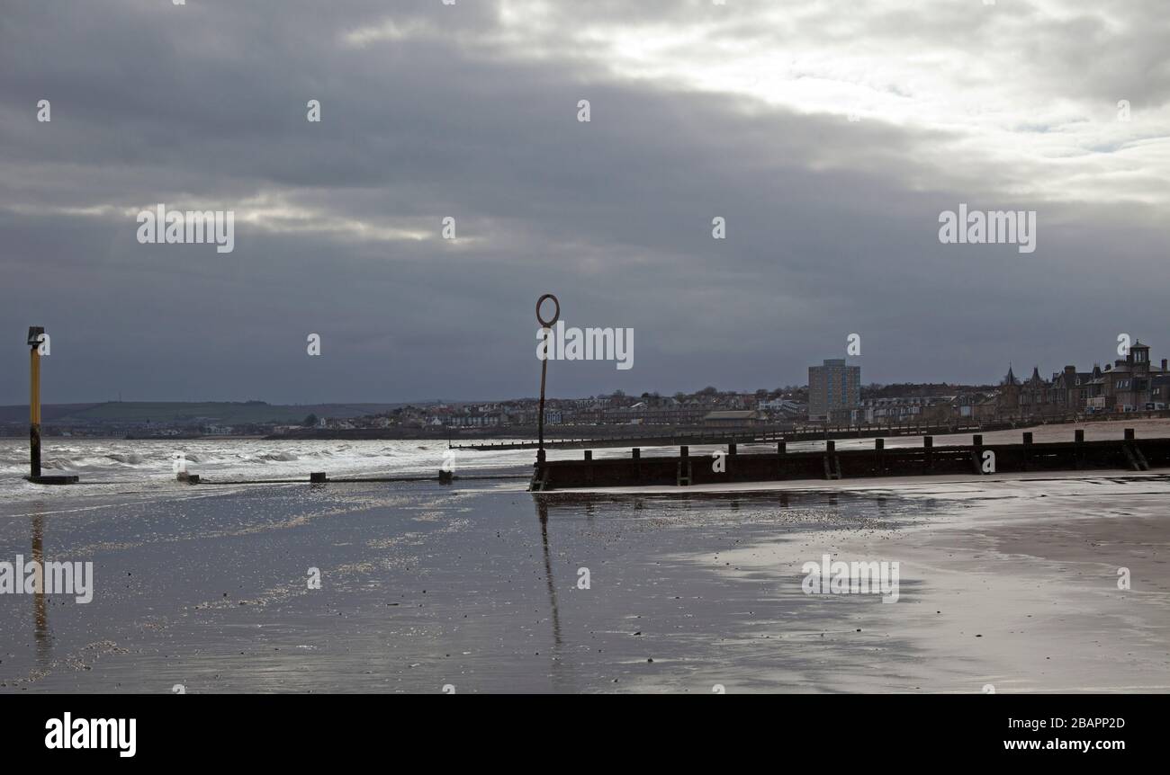 Portobello, Edimburgo, Scozia, Regno Unito. 29 marzo 2020. Moody vuota spiaggia in questa mattina nuvolosa a 3 gradi centigradi con il raggio occasionale di sole che sbirciano attraverso le nuvole. Normalmente, ci sarebbero molti più camminatori del cane e pedoni che sono visibili questa mattina. Foto Stock