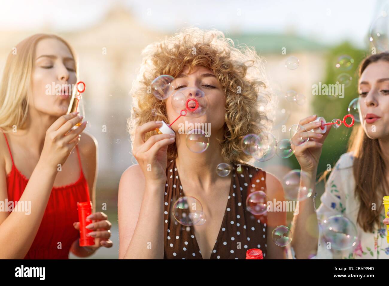 Giovani donne che soffiano bolle di sapone all'aperto Foto Stock