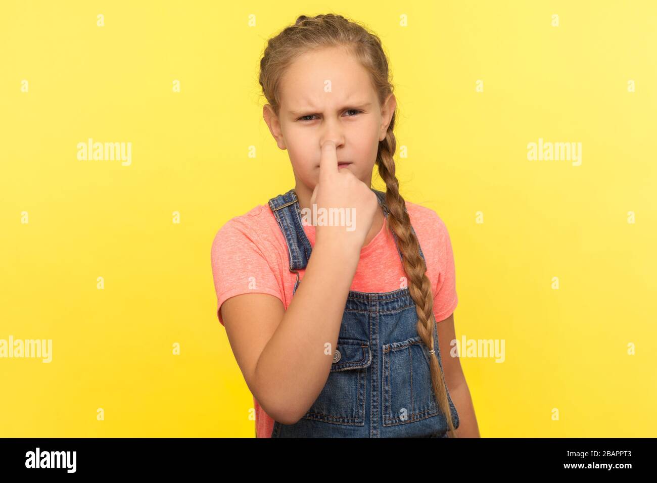 È la menzogna! Ritratto di ragazza piccola disgrunled con treccia in tute di denim che toccano il suo naso e che guarda arrabbiato, gesturante siete bugiardo, non inganno Foto Stock