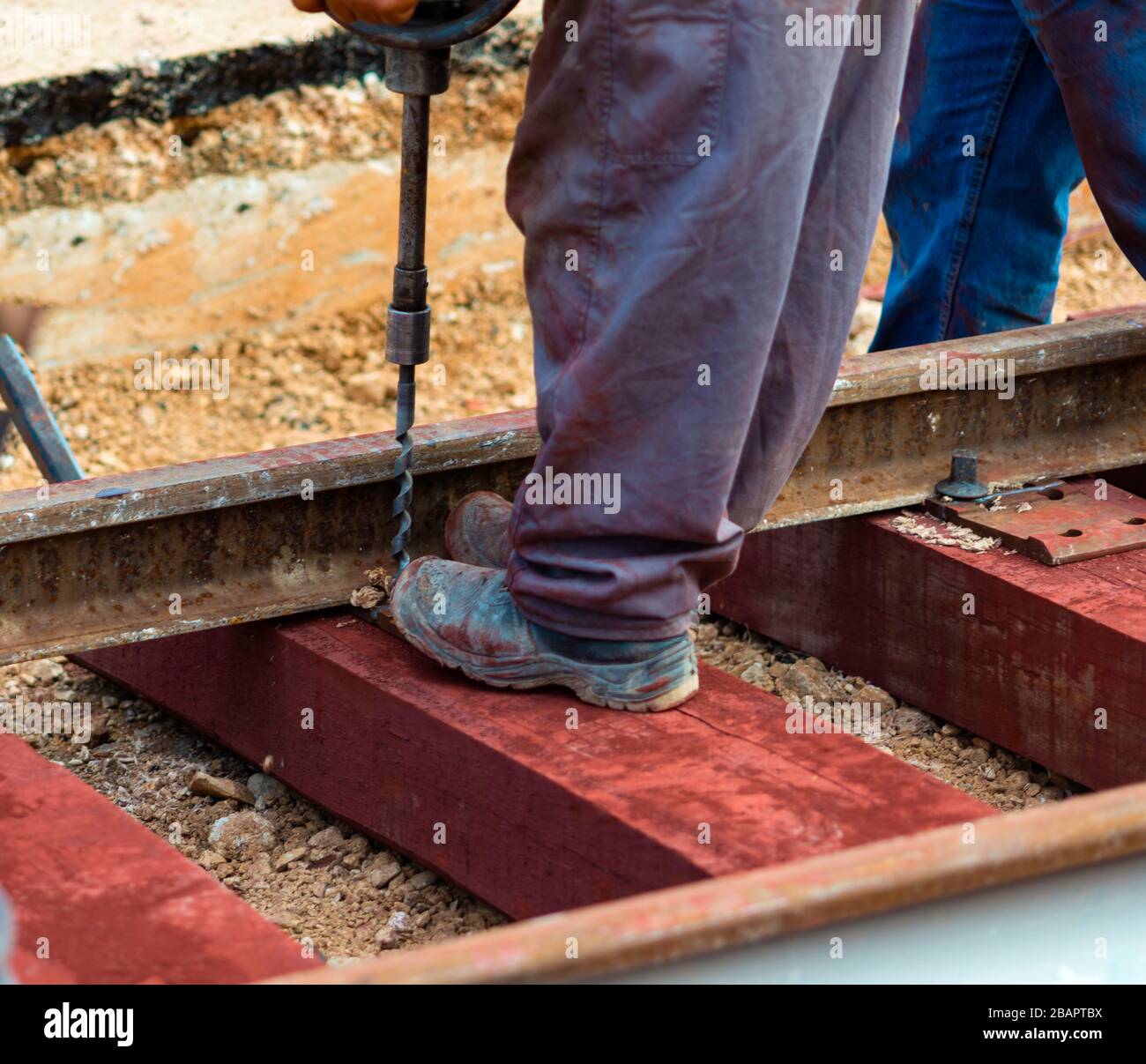 Lavoratori ferroviari che bullonano la ferrovia a binario. Dettaglio lavoratore con macchina di perforazione leggera per traversine portatili Foto Stock