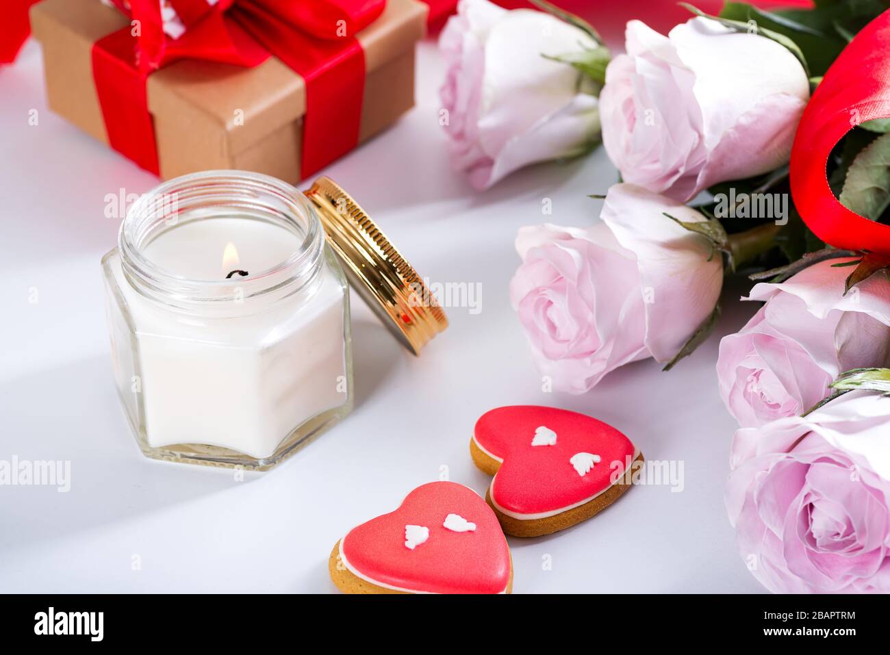 Biscotti fatti in casa di San Valentino cuore, rose rosa e candela su tavola bianca, copia spazio Foto Stock