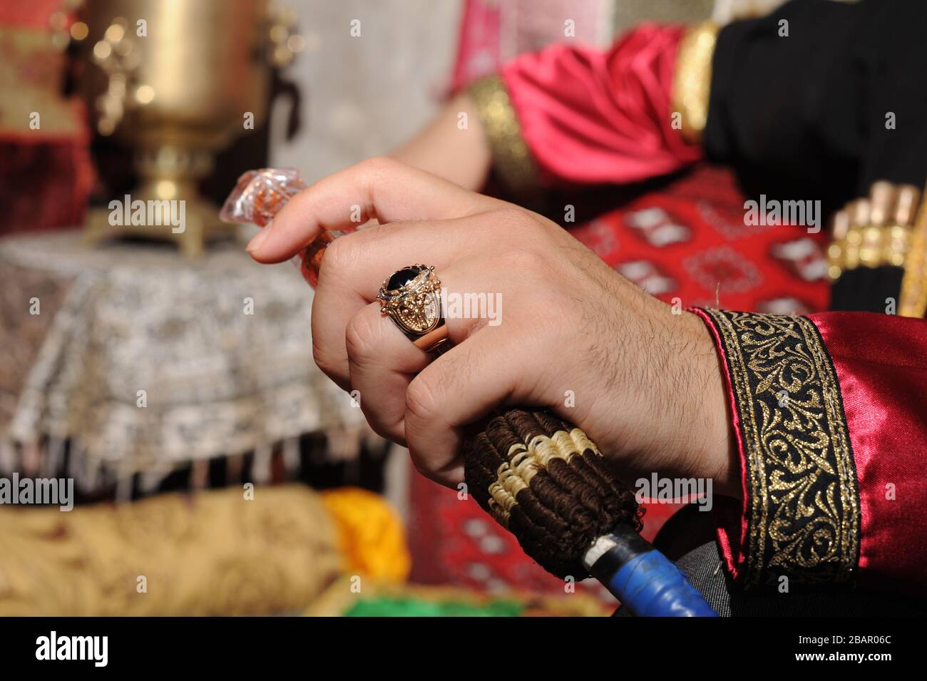 Un tubo di hookah nelle mani di un fumatore in vestiti nazionali azerbaigiani Foto Stock