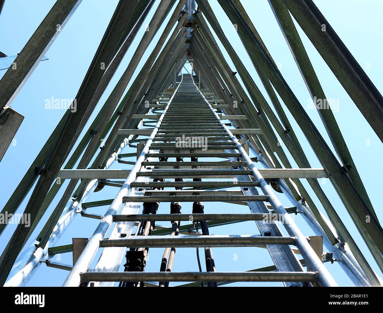 La fotografia offre una prospettiva verso l'alto della struttura interna di una torre di telecomunicazioni. L'immagine rivela la complessa struttura in acciaio che c Foto Stock