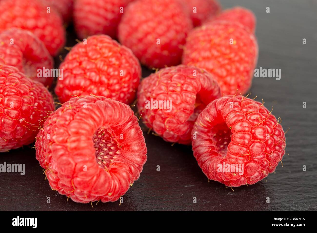 frutta fresca di lampone rosso su piastra nera di ardesia primo piano fuoco selettivo Foto Stock