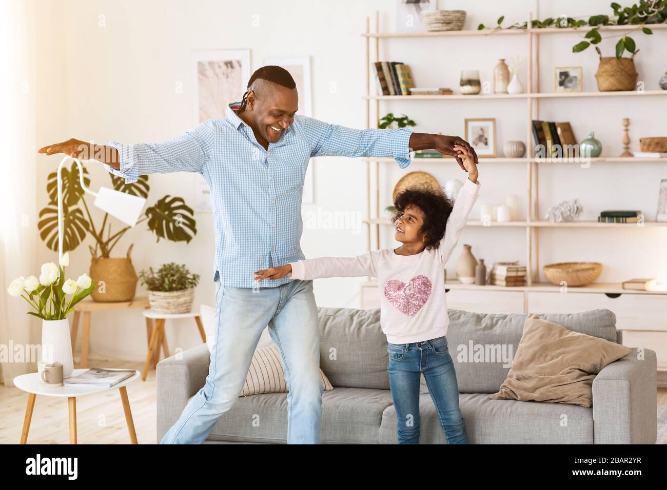 Soggiorno a casa come preferisci. Uomo americano africano anziano che balla con la sua nipote all'interno Foto Stock