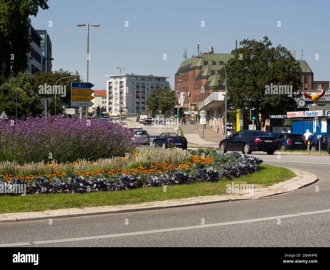 Alla rotonda Lindenplatz di Lübeck Germania, il traffico si combina con piante e fiori bellissimi Foto Stock