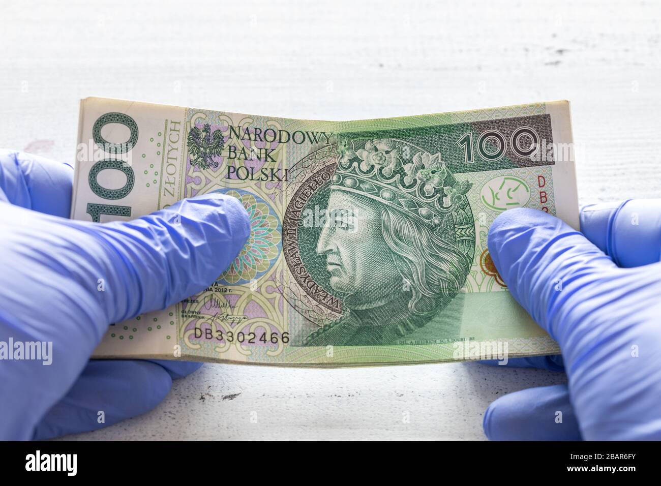 Denaro polacco, cento zlotys banconote tenute in guanti di gomma. Il concetto di economia e minacce finanziarie durante la pandemia di Coronavirus Foto Stock