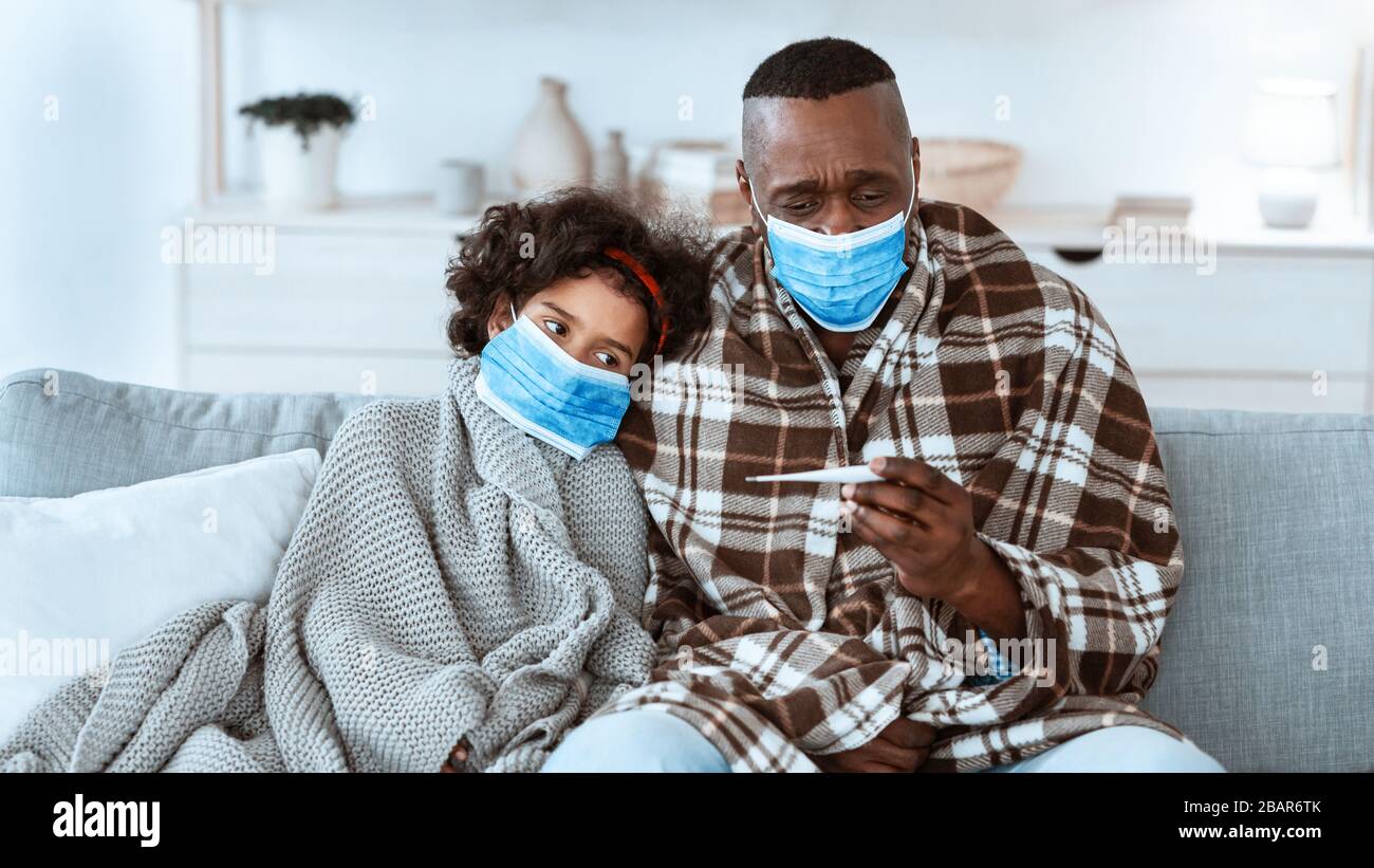 Epidemia mondiale. L'uomo africano americano maturo ed il suo grandchild che indossano le maschere e che soffrono dal virus nel paese Foto Stock