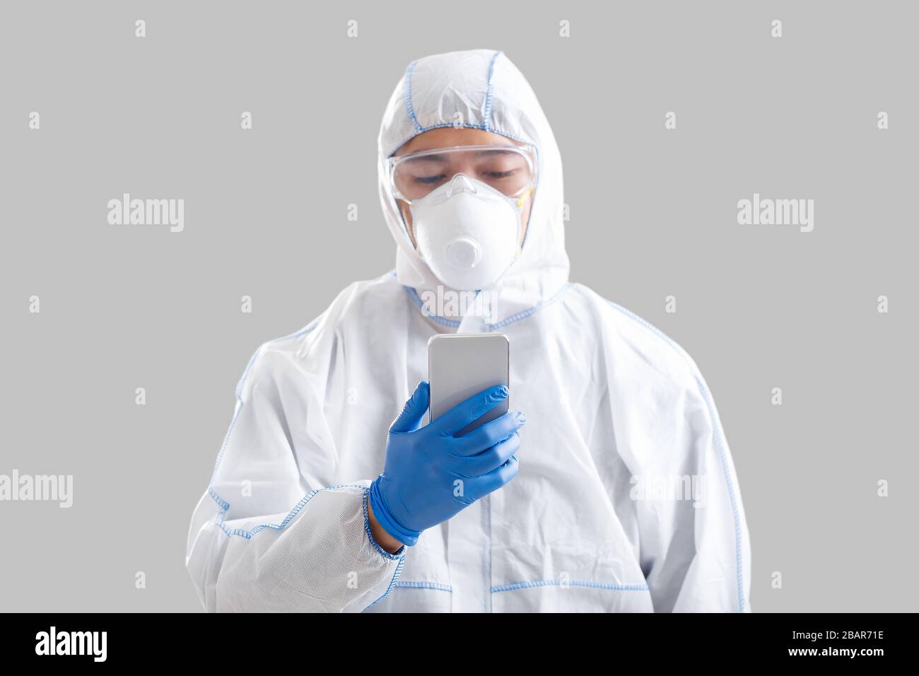 L'uomo asiatico in tuta protettiva legge notizie sullo smartphone Foto Stock