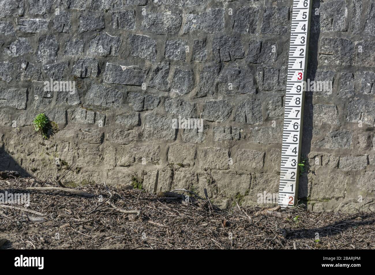 Misuratore del livello dell'acqua del fiume collegato alla parete di sbarramento in pendenza sul fiume Fowey a Lostwithiel. Metafora dell'aumento dei livelli dell'acqua, difese da alluvioni. Foto Stock