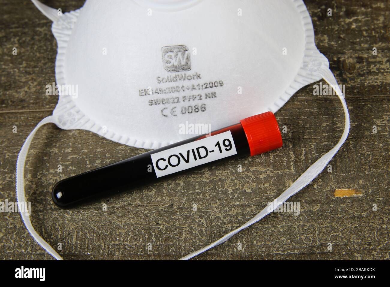 Viersen, Germania - 28.marzo 2020: Maschera ffp2 certificata CE isolata con fiala di campione di sangue covid-19 su tavola di legno Foto Stock