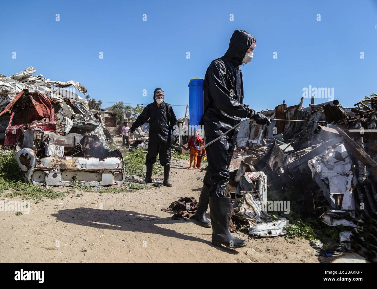 Gaza, Palestina. 29 marzo 2020. Gli operatori sanitari palestinesi vestiti con tute protettive spray disinfettanti come misura precauzionale contro la diffusione di coronavirus nelle baraccopoli di Khan Yunis nella striscia meridionale di Gaza.le ultime cifre dell'Organizzazione Mondiale della Sanità (OMS) mostrano più di 3,300 casi confermati in Israele e più di 80 nei territori palestinesi occupati. Credit: SOPA Images Limited/Alamy Live News Foto Stock