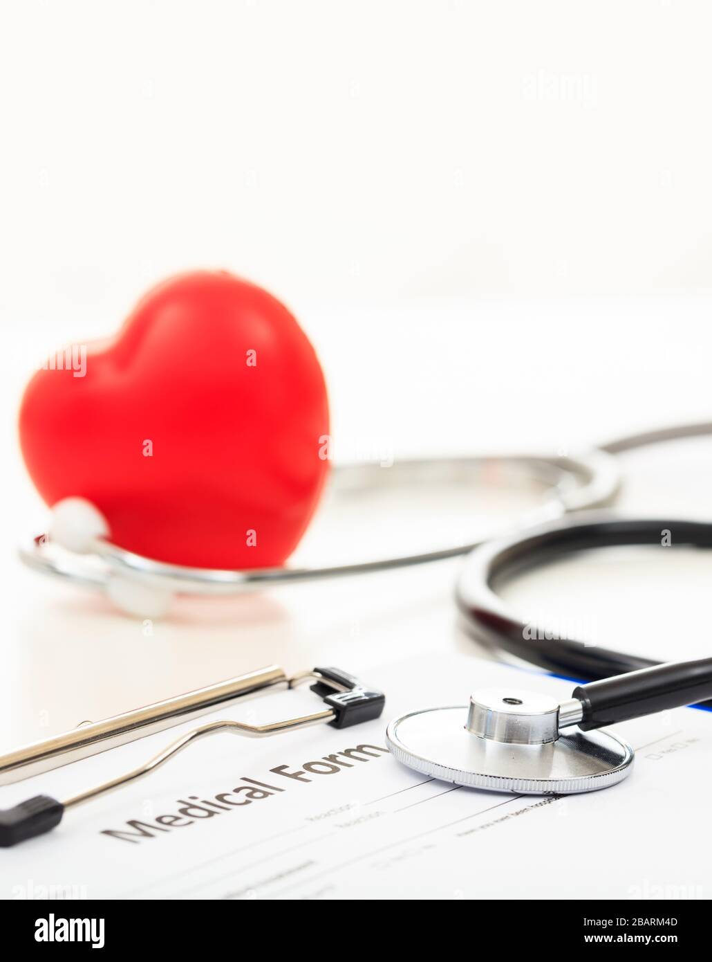 Salute di cuore, concetto di assicurazione. Cuore rosso e stetoscopio su una forma medica, ufficio medico, vista primo piano Foto Stock