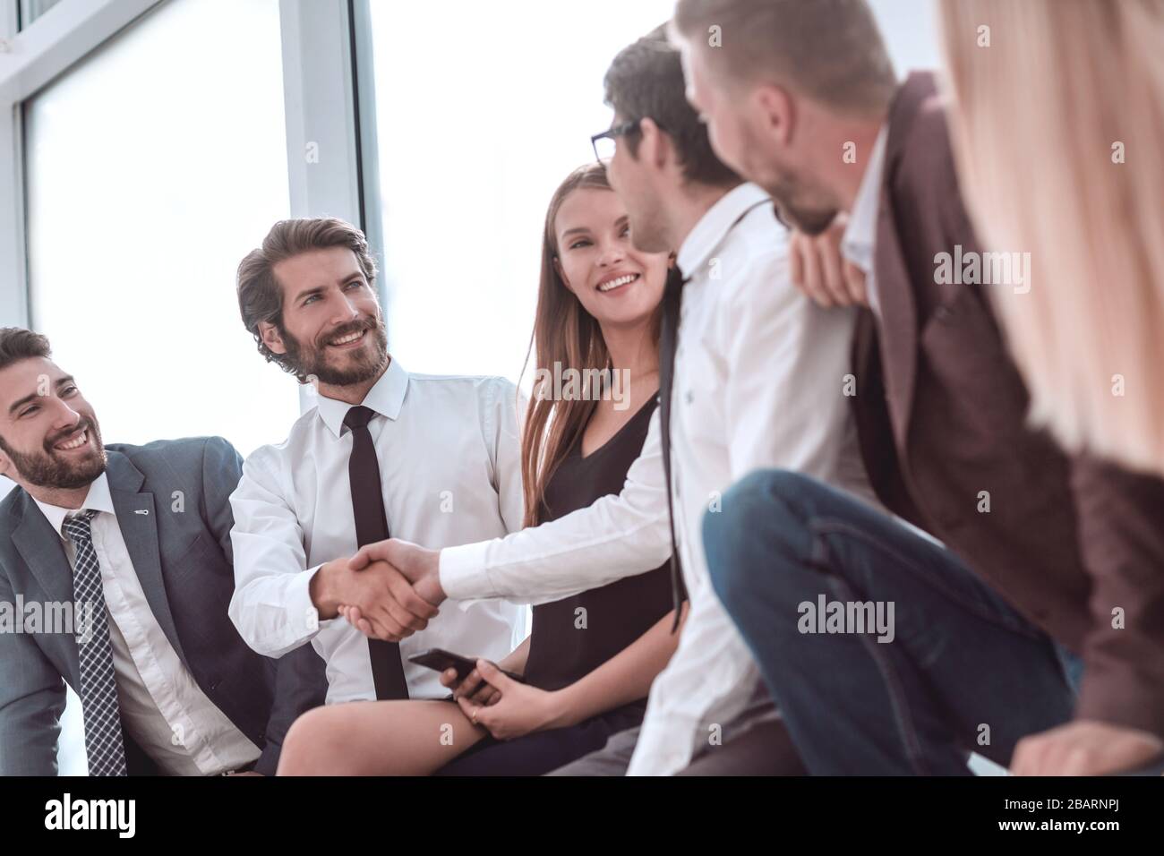 I giovani uomini di affari che stringono le mani mentre è seduto nella lobby di office Foto Stock