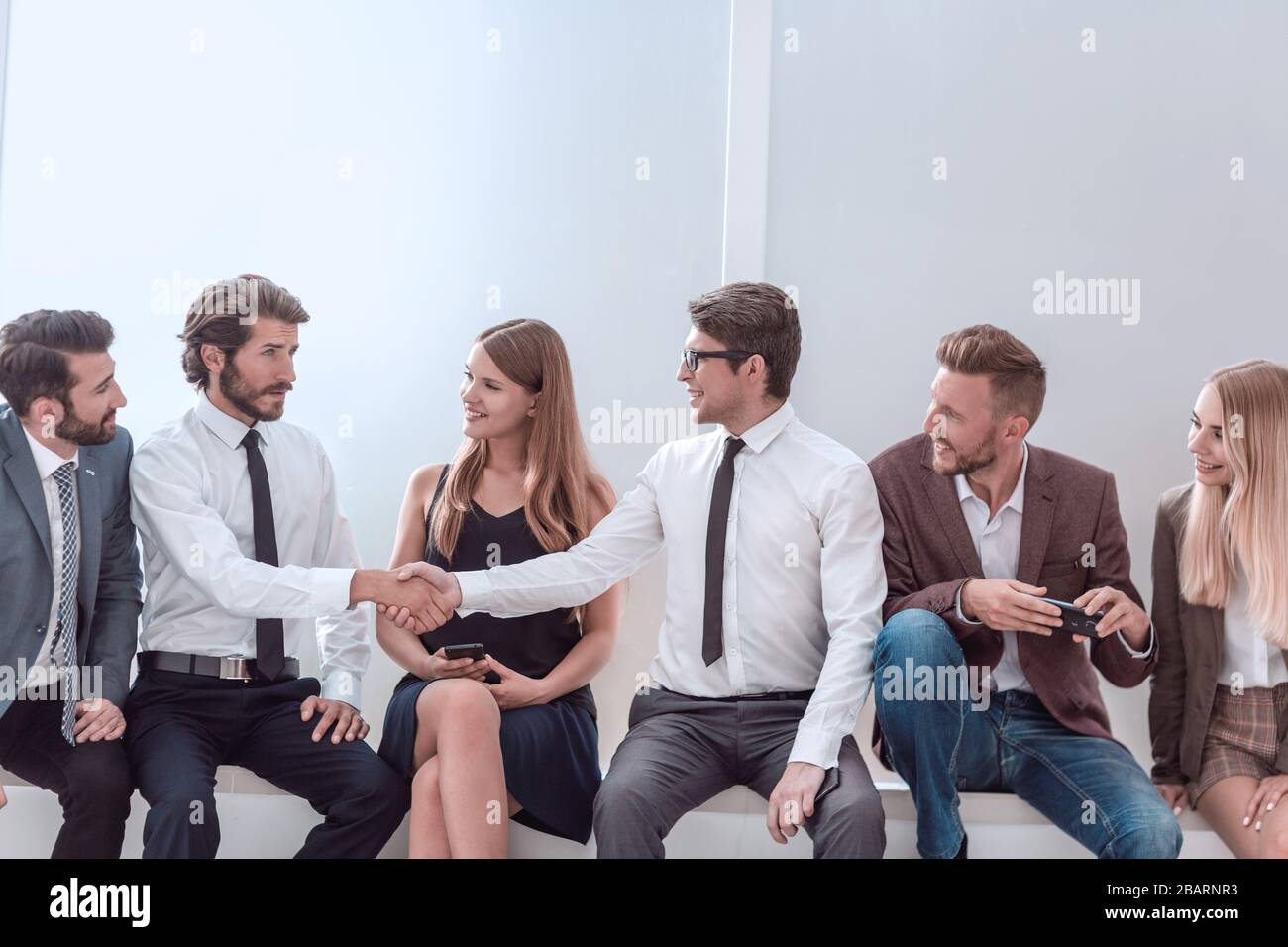 I giovani uomini di affari che stringono le mani mentre è seduto nella lobby di office Foto Stock