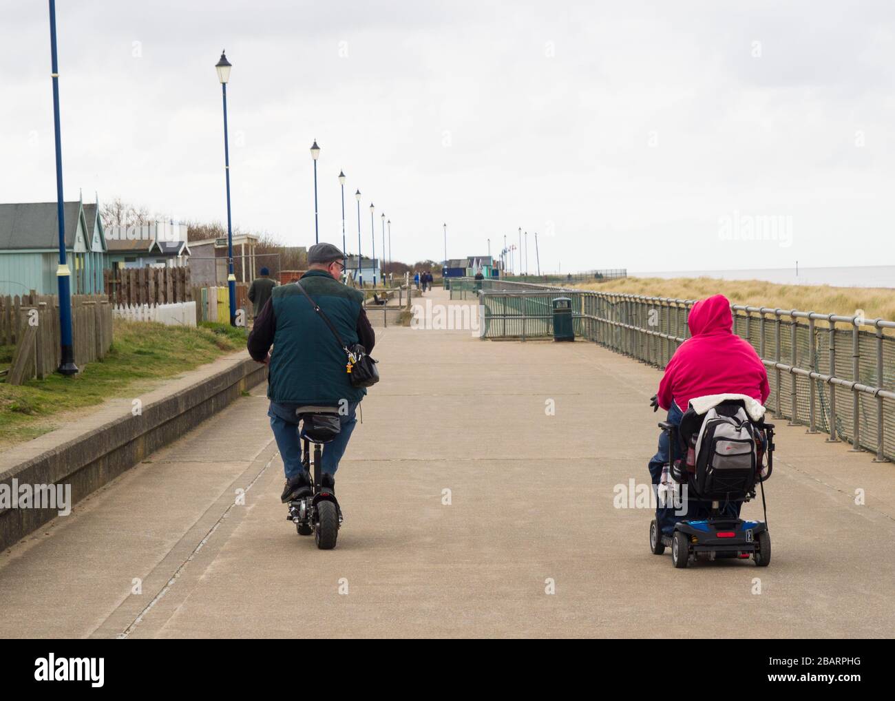 Coppia su scooter da mobilità lungo la passeggiata Sutton on Sea, Lincolnshire, Regno Unito Foto Stock