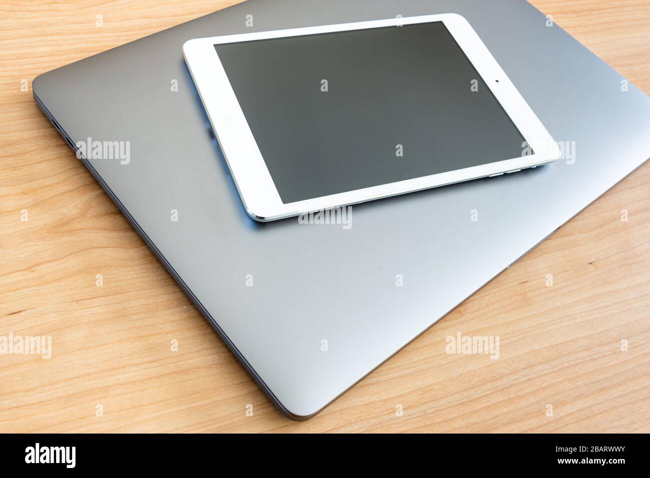 Un tablet bianco e un computer portatile su una superficie in legno. Foto Stock