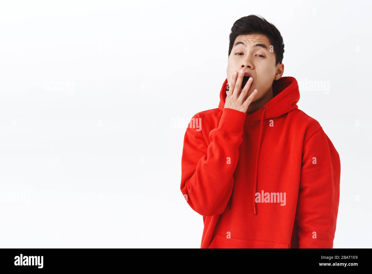 Girovita ritratto di ragazzo hipster annoiato sonnolento, giovane uomo asiatico che brulica e la copertura aperta bocca, guardare fotocamera con la faccia noiosa, svegliarsi presto, bisogno Foto Stock
