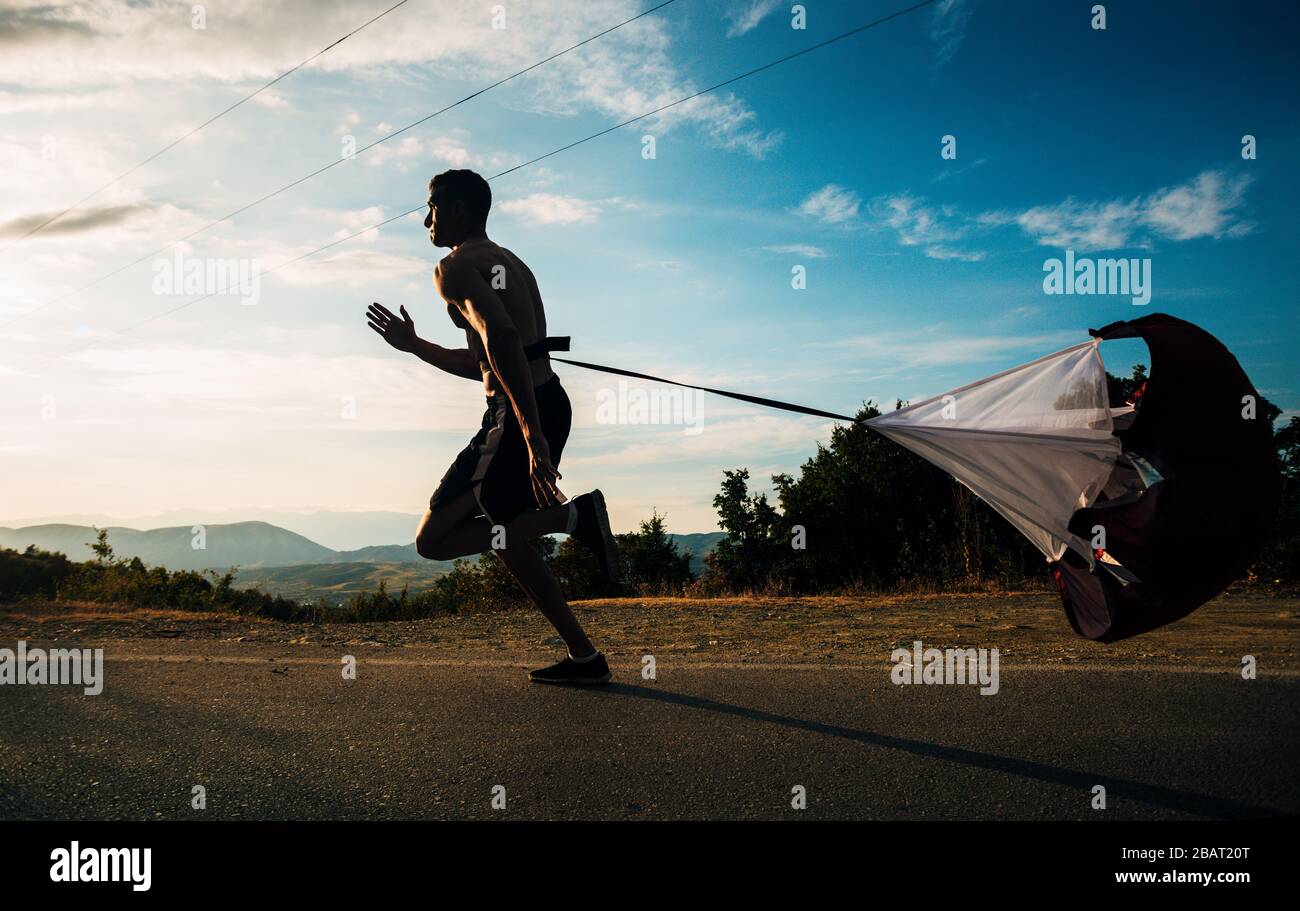 Atleta jogger allenarsi cardio con paracadute sport salire su cross gara di campagna in salita all'aperto Foto Stock