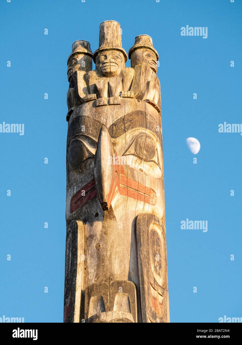 Totem pole al tramonto e moonrise: La cima di un grande totem scolpito della costa occidentale in mostra al Museo UBC di Antropologia contro un cielo blu. Foto Stock