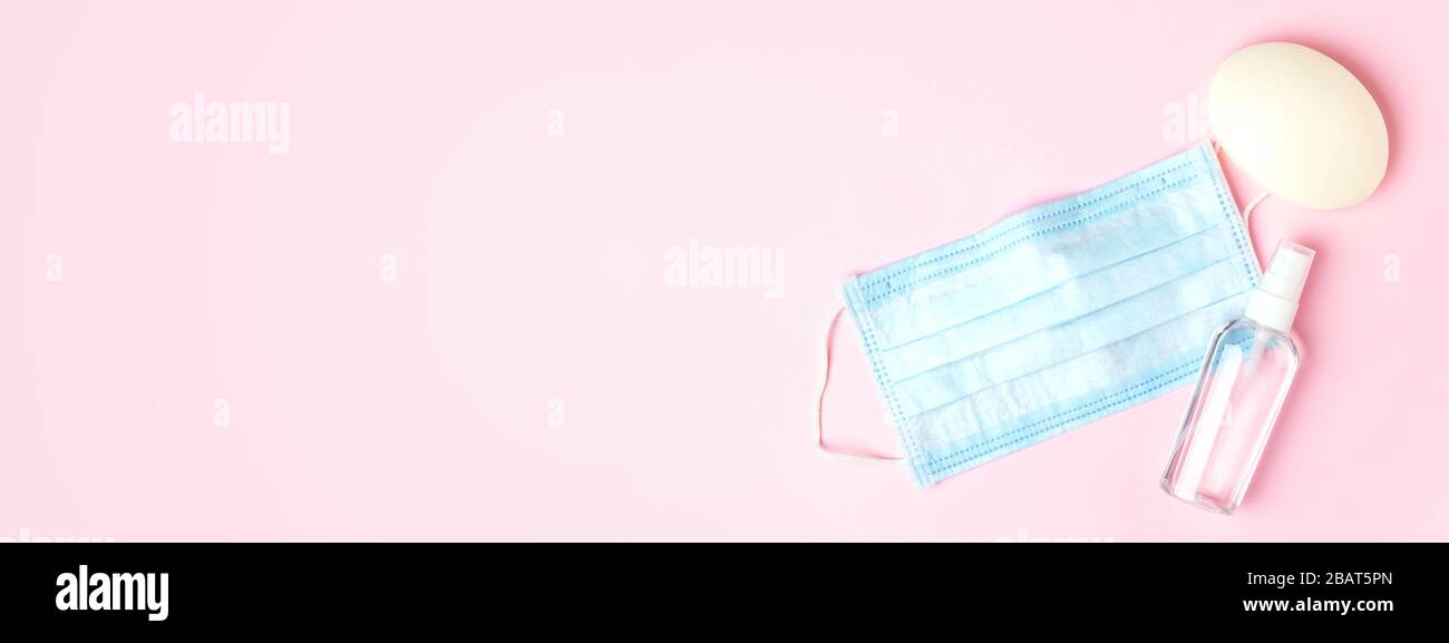 Maschera medica blu, sapone e antisettico su sfondo rosa. Concetto di protezione contro il virus. Banner per il sito Web. Foto Stock