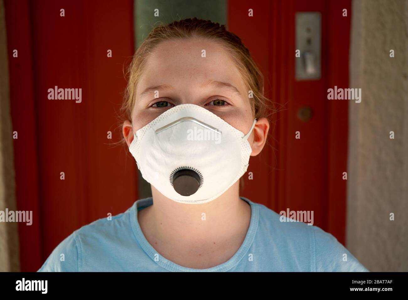 Ragazza giovane che indossa la maschera del viso a casa Foto Stock