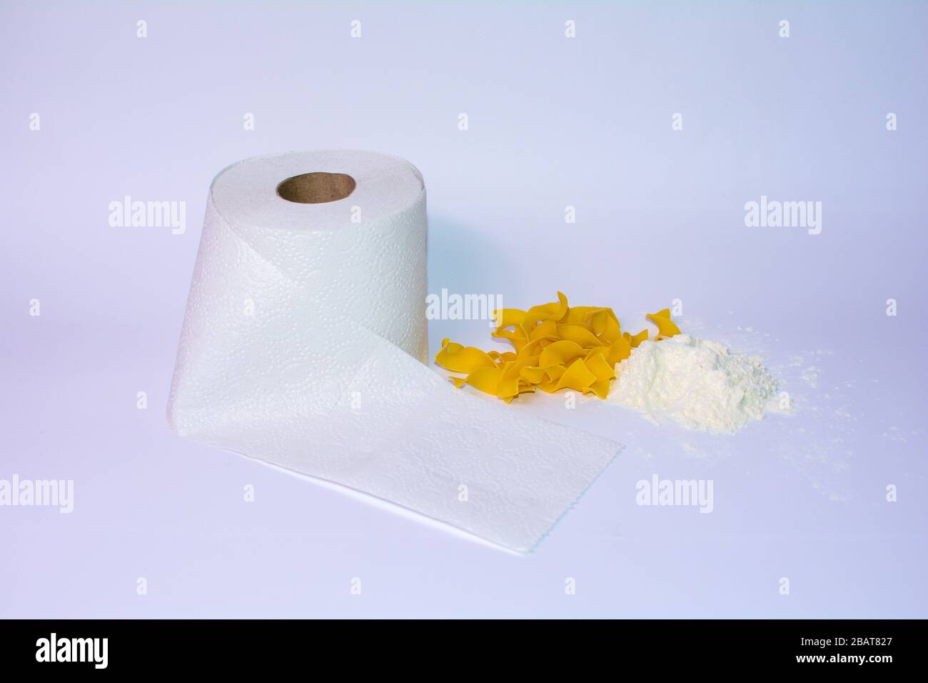 Un rotolo di carta igienica, pasta e farina su sfondo bianco - acquisti di criceti in tempi critici Foto Stock