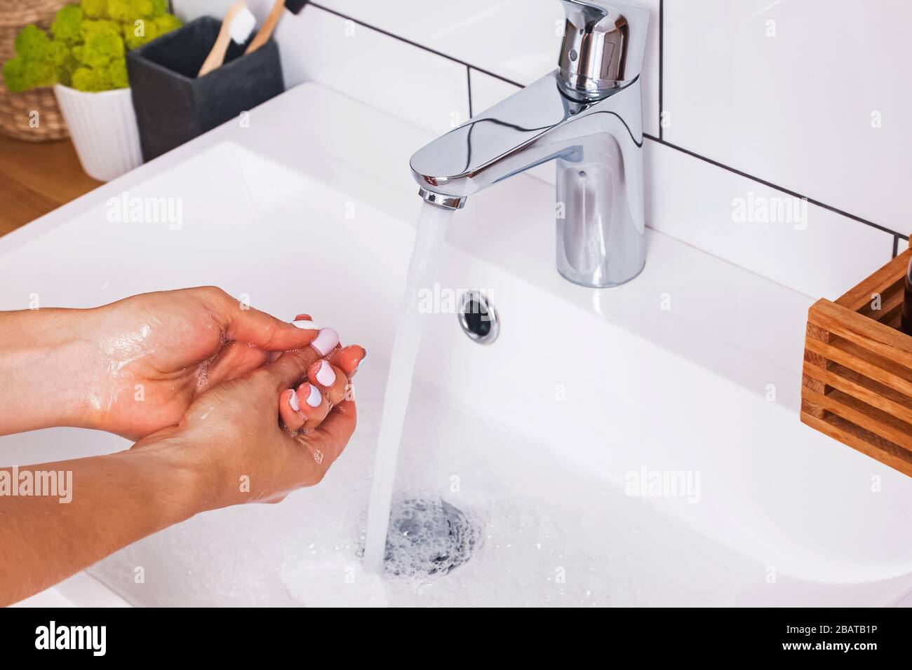 Donna lavando le mani con sapone in un bagno bianco Foto Stock
