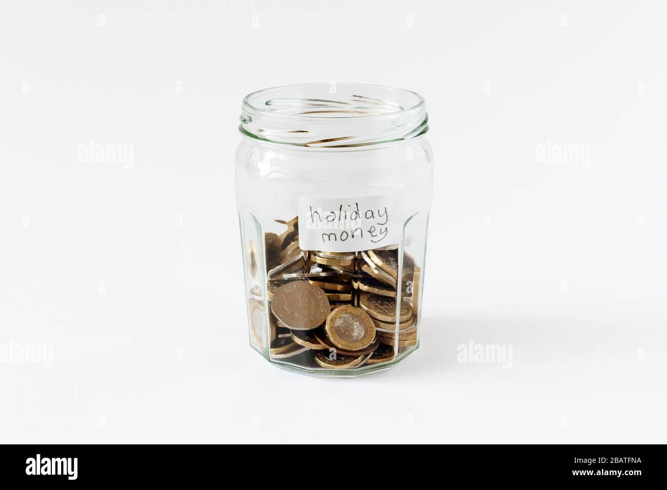 Un jar di marmellata di vetro contenente monete britanniche, con un'etichetta scritta a mano 'denaro per le vacanze' Foto Stock