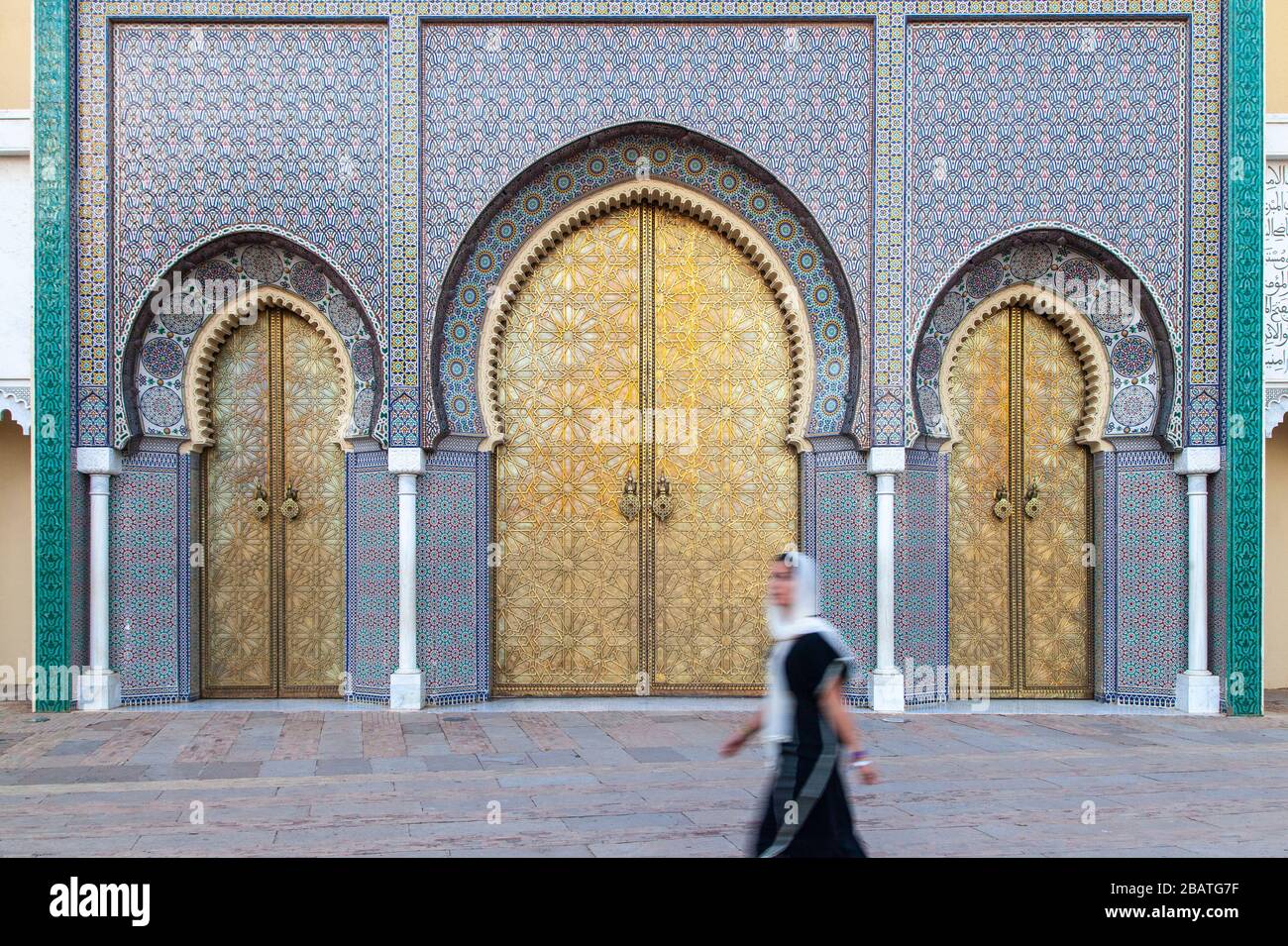 Una giovane donna velata che cammina davanti al cancello del Palazzo reale a Fes Foto Stock