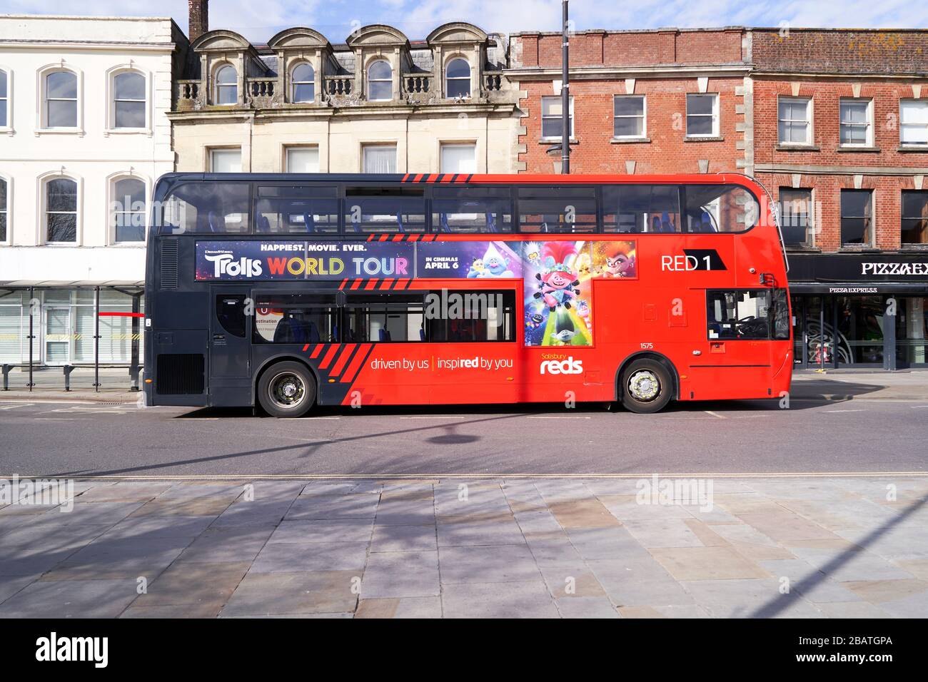 Autobus rosso a due piani vuoto con film pubblicizzato sul lato Foto Stock