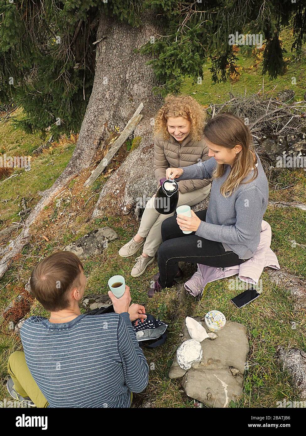 Gruppo giovane di 3 persone su una montagna dopo aver fatto una pausa con tee e caffè Foto Stock