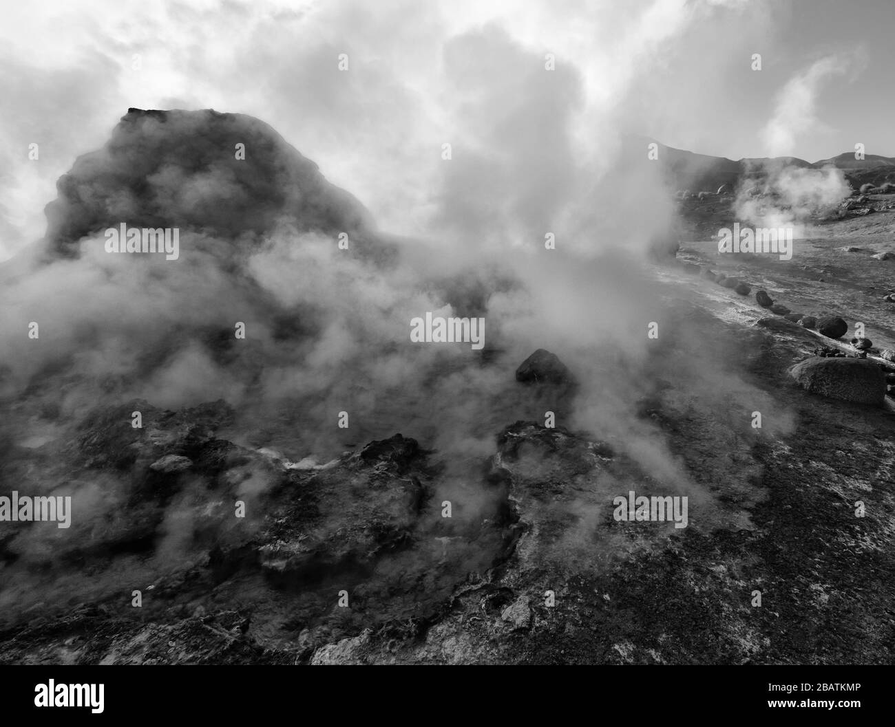 Il vapore sorge da un geyser intorno a un masso all'alba, El Tatio Geyser Field, Atacama Desert, Cile (bianco e nero) Foto Stock