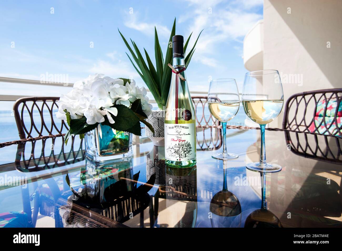 Una bottiglia di vino con due bicchieri offre un'invitante seduta con vista sull'oceano Foto Stock