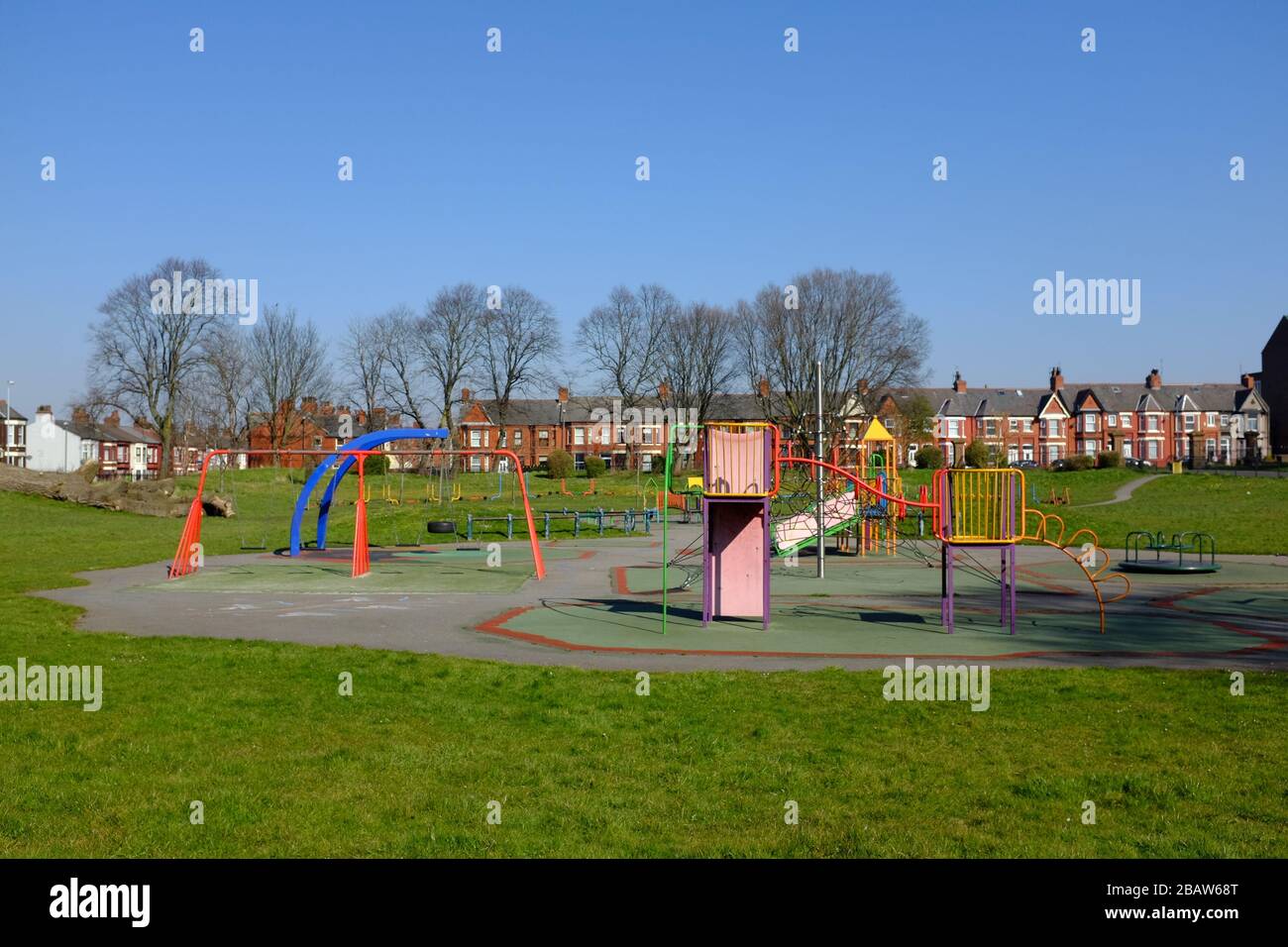 Derby Park a Bootle Liverpool è quasi deserta e l'area giochi per bambini è chiusa. La gente tiene la loro distanza al supermercato a causa di COVID-19. Foto Stock