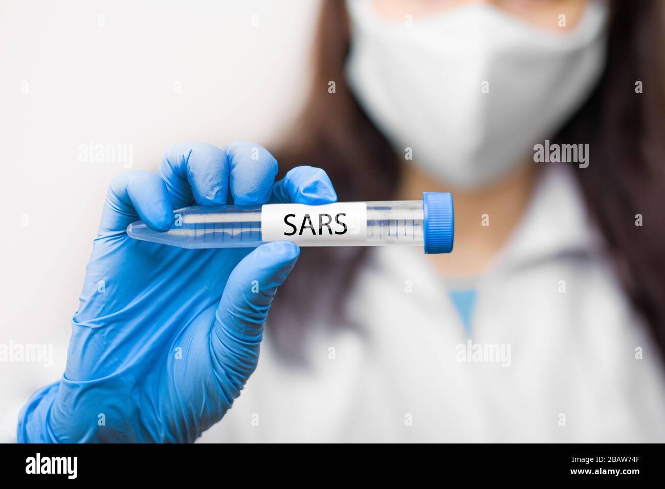Provetta con vaccino contro il coronavirus, 2019-nCoV, SARS-nCov, COVID-19 in maschera protettiva e guanti blu per scienziato. Foto Stock