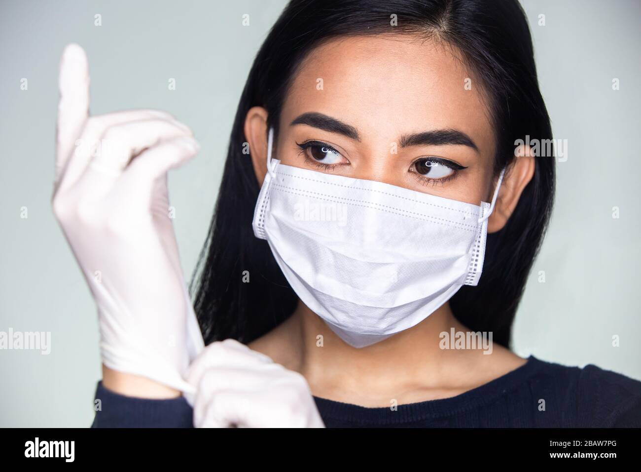 Epidemia di coronavirus: Una donna asiatica che indossa guanti di gomma medica e una maschera monouso per evitare virus contagiosi. Foto Stock