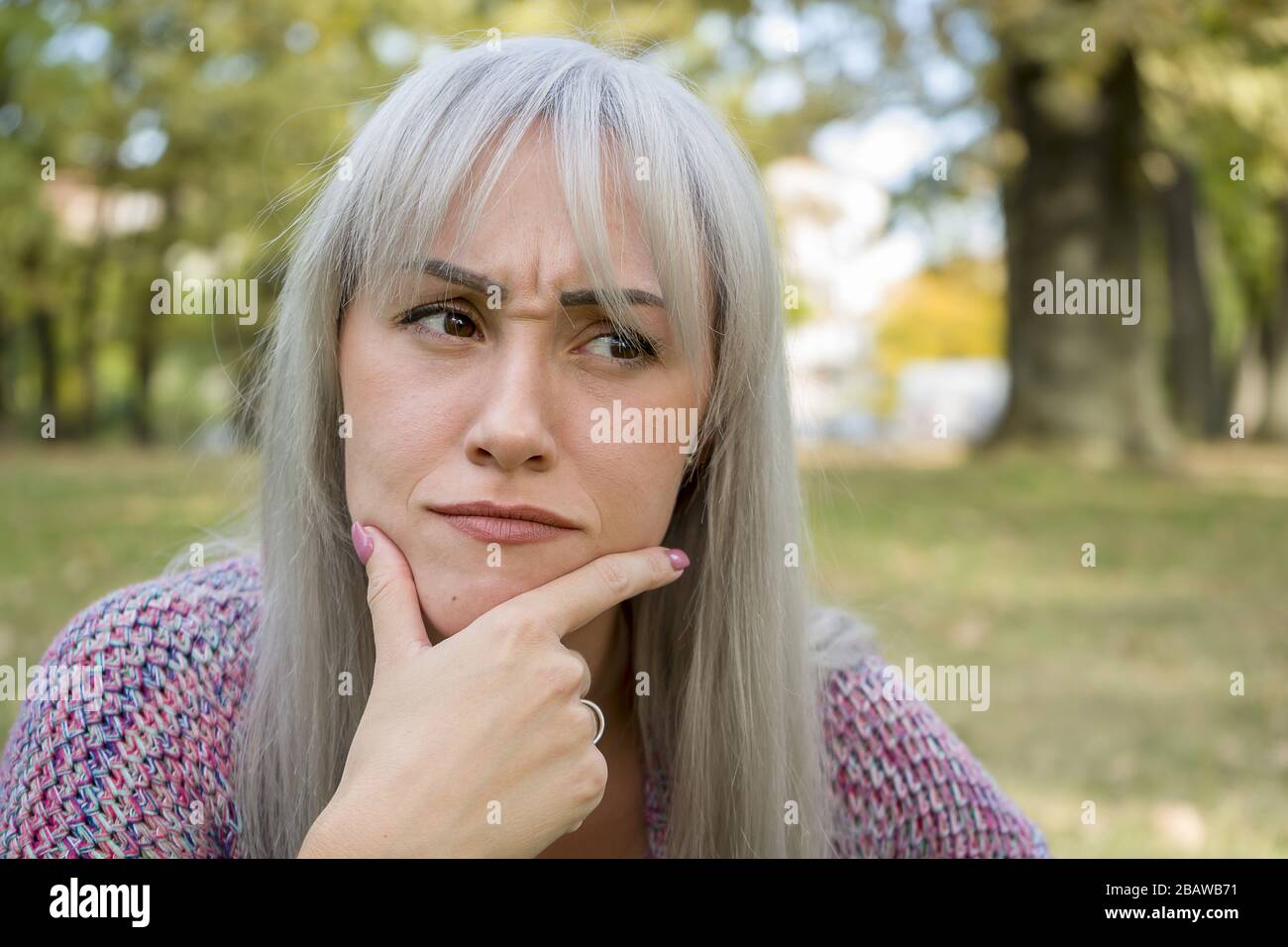 Ritratto all'aperto di una donna che fa volti divertenti. Capelli d'argento. Foto Stock