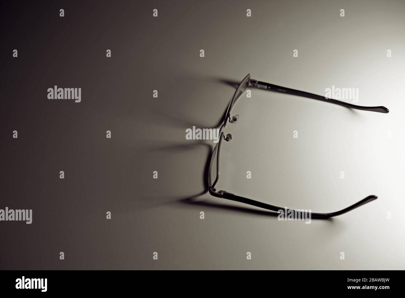 Un paio di occhiali che gettano le ombre sul tavolo bianco. Concetto: Minimalismo nella fotografia. Foto Stock