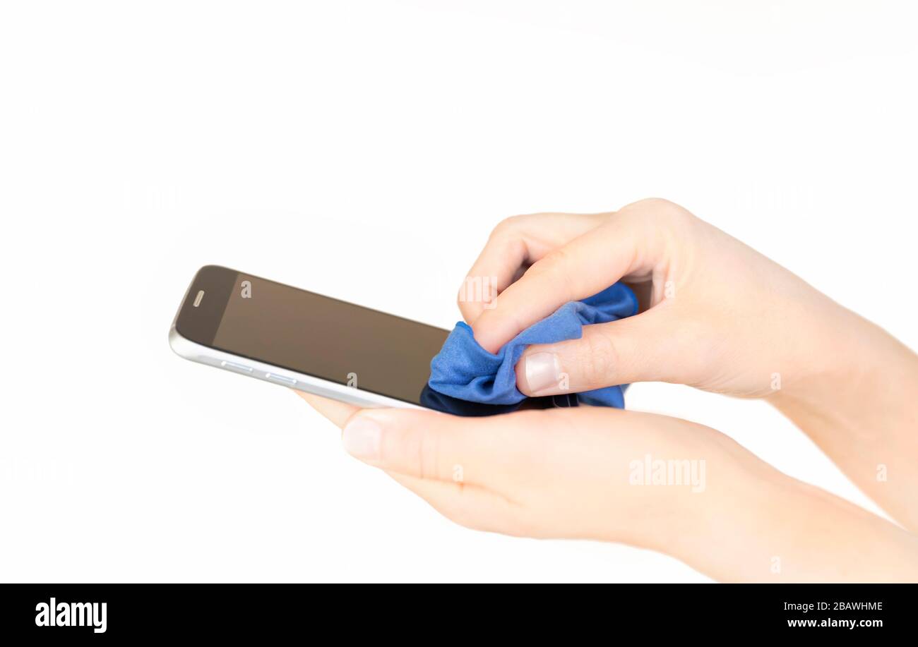 Una persona che pulisce il telefono mobile per impedire la diffusione di germi, batteri e virus corona. Foto Stock