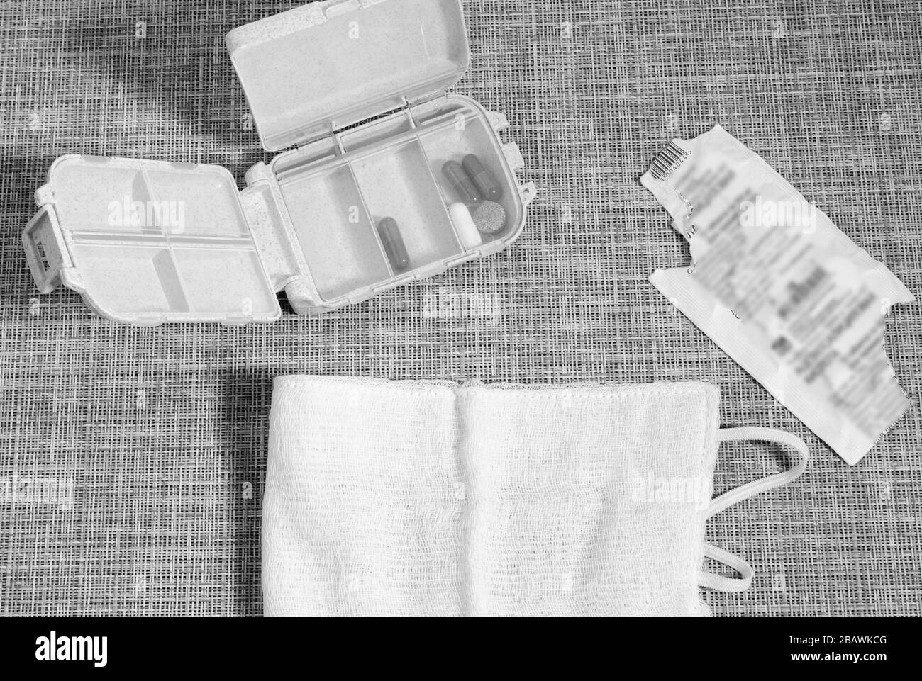 Scatola per pillola e maschera medica. Pillole sul tavolo. Texture in vimini. Immagine in bianco e nero. Foto Stock
