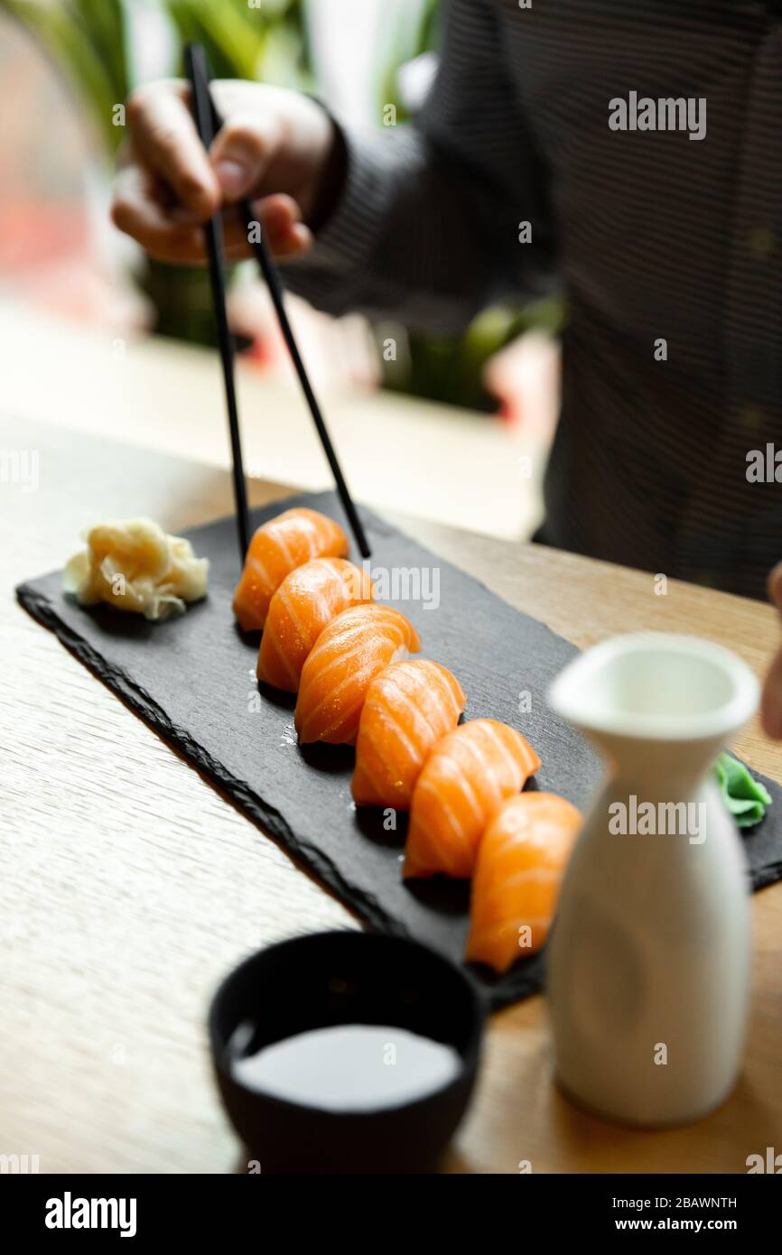 Sushi di salmone uomo al tavolo del ristorante. L'uomo asiatico mangia sushi di salmone in un ristorante asiatico. Foto Stock