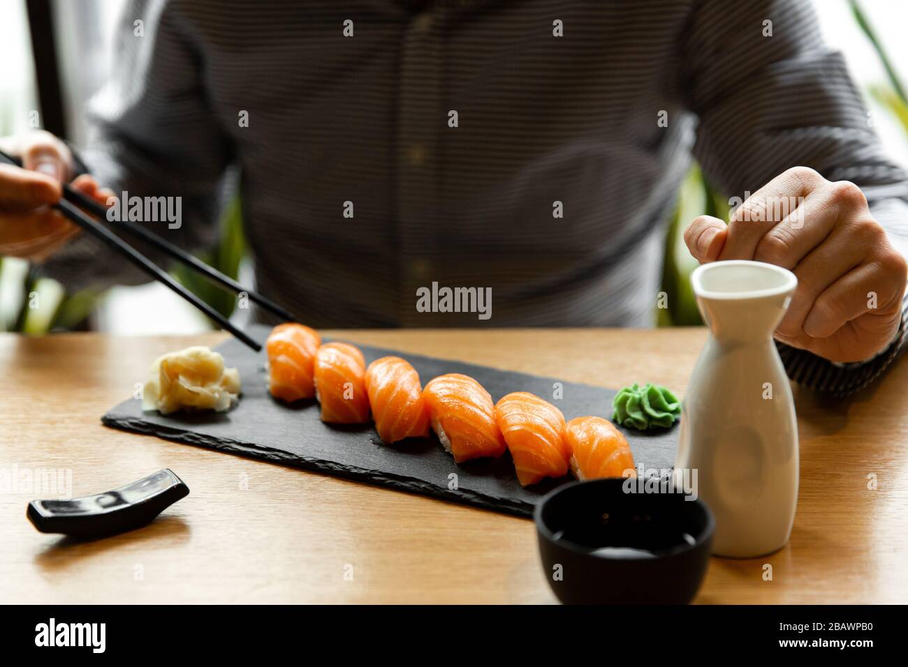 Sushi di salmone uomo al tavolo del ristorante. L'uomo asiatico mangia sushi di salmone in un ristorante asiatico. Foto Stock