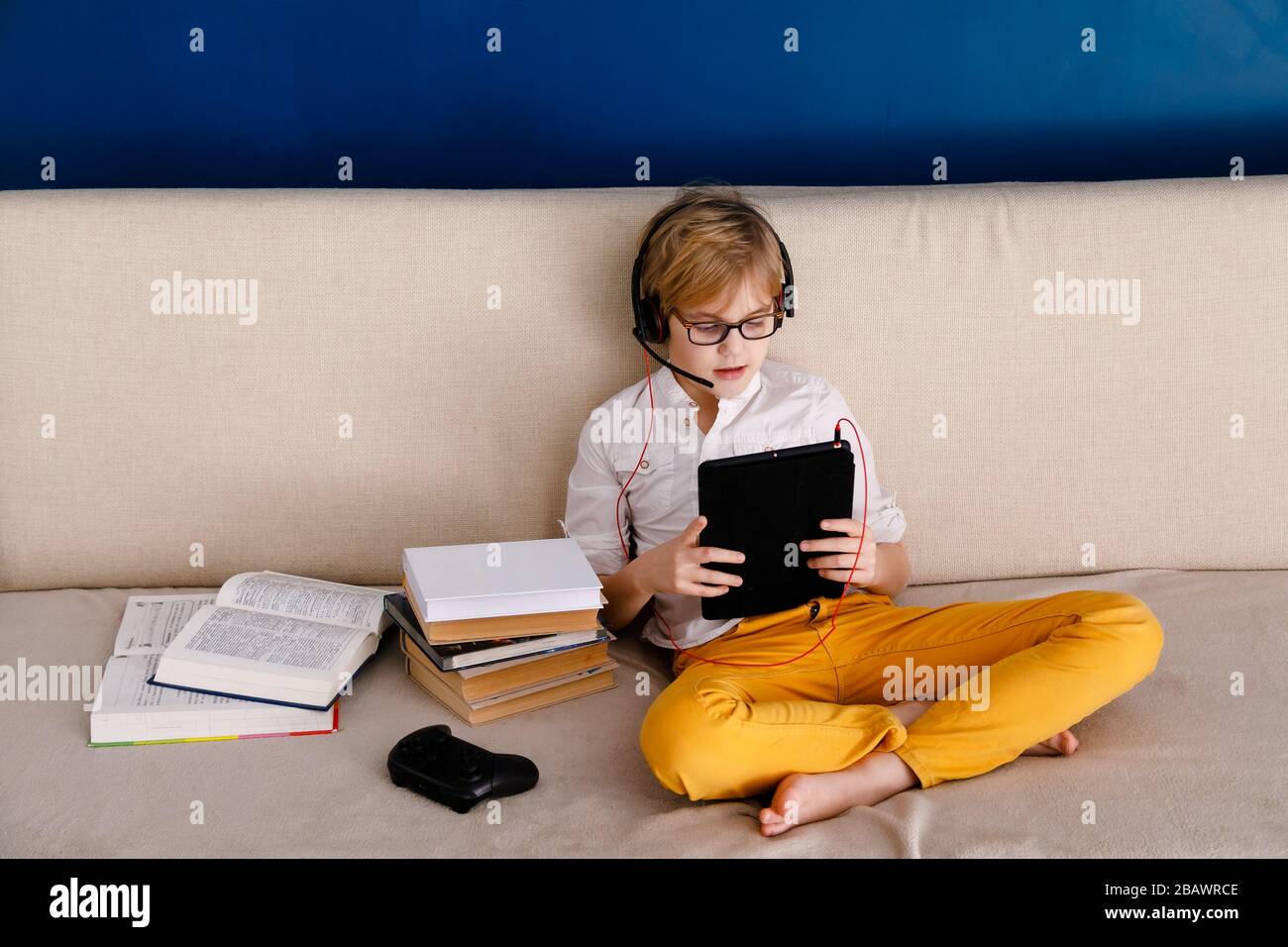 Ragazzo in occhiali su auto isolamento utilizzando tablet digitale per i suoi compiti, per la ricerca di informazioni su internet, mentre la scuola di durante covid-19 serratura dow Foto Stock