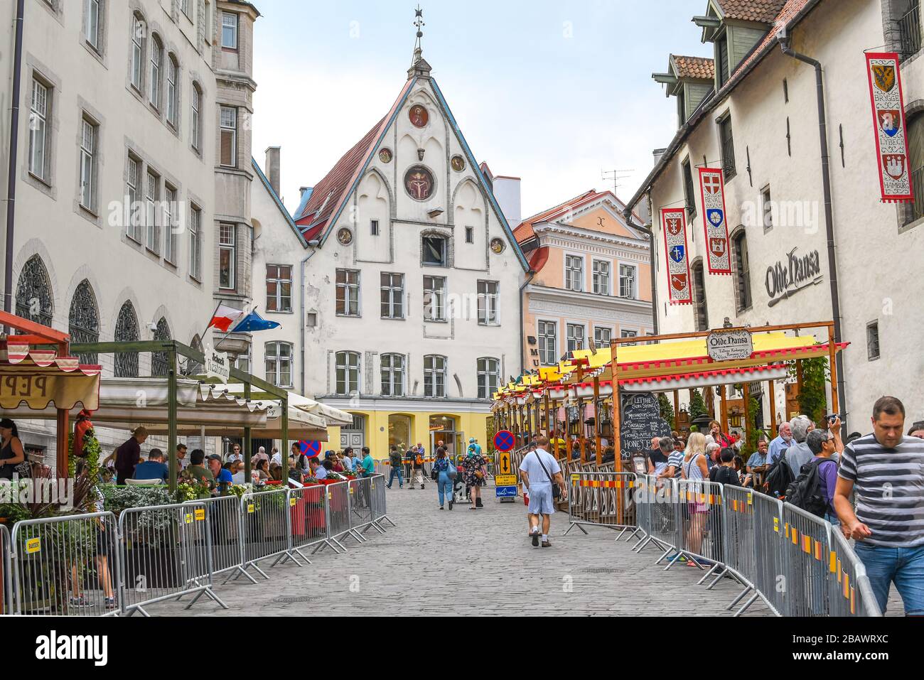 Affascinante strada di caffè e negozi divisi da barricate per la Maratona di Tallinn con la casa medievale del Vescovo in vista a Tallinn Estonia. Foto Stock