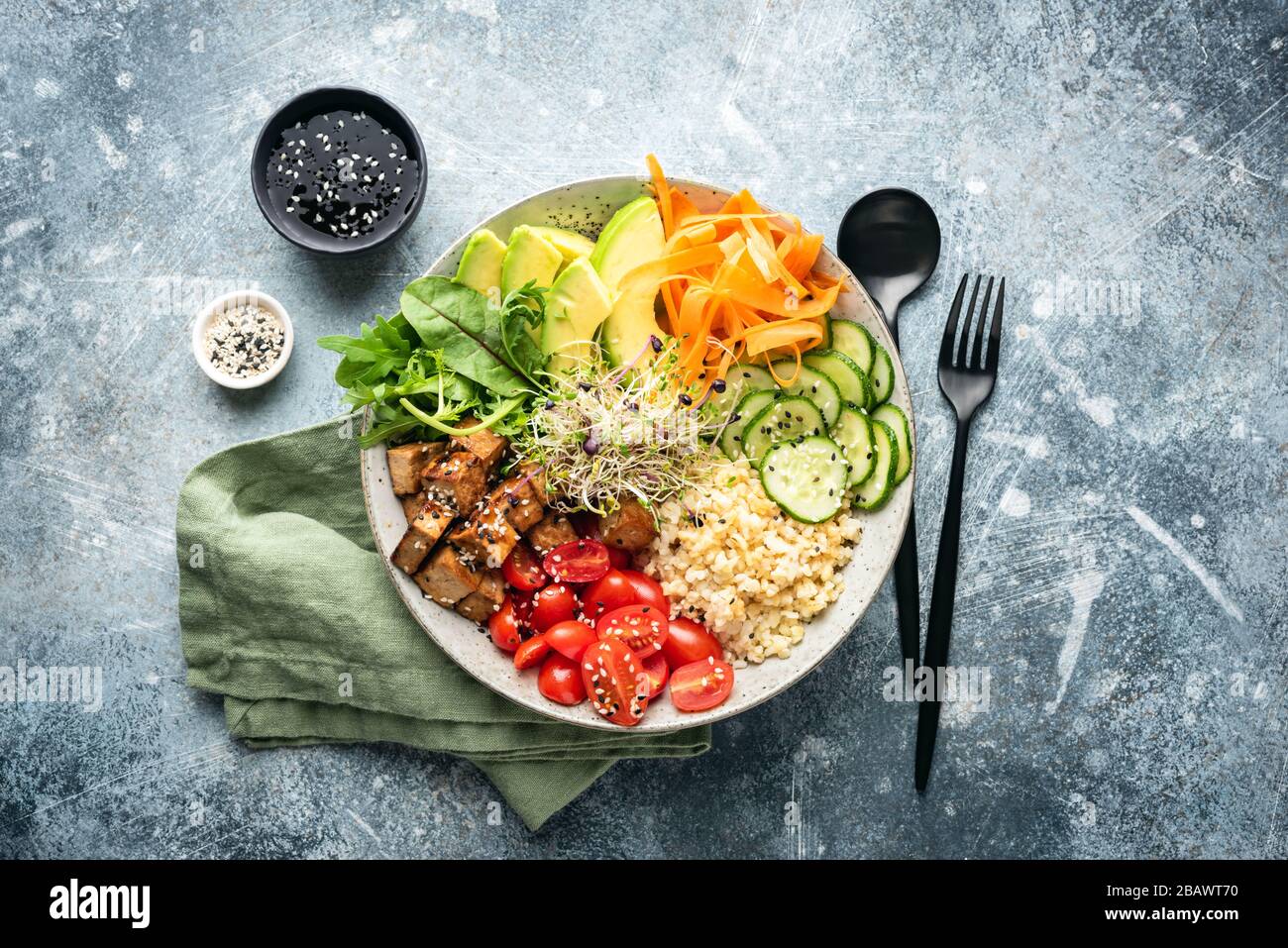 Ciotola di buddha vegano con tofu, verdure, avocado servito con salsa di soia e semi di sesamo. Vista dall'alto Foto Stock