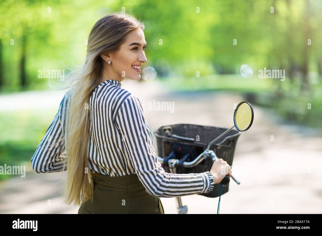 Attraente giovane donna con la sua bicicletta in città Foto Stock