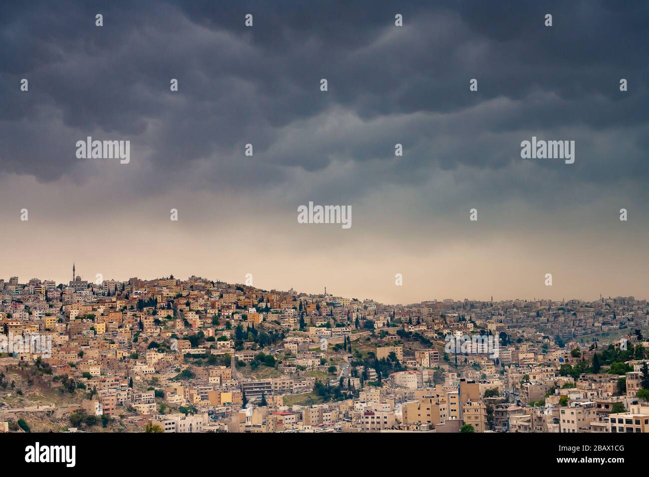 Minacciose nubi di tempesta che si profilano su colline densamente popolate della città vecchia di Amman, Giordania. Foto Stock