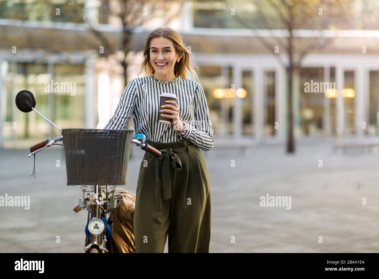 Attraente giovane donna con la sua bicicletta in città Foto Stock