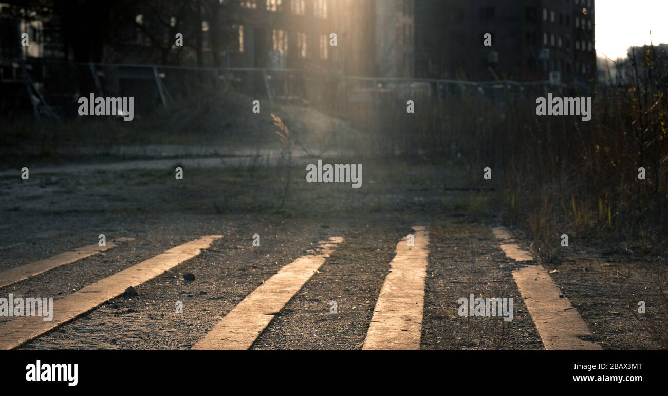 Vista ad angolo basso di una strada della città deserta di notte illuminata da fasci di luce da finestre di appartamenti illuminati con file di pavimentazione in ghiaia nel foregr Foto Stock